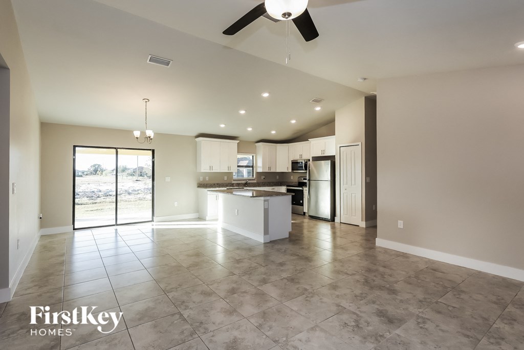 an open kitchen and living room with tile flooring and a ceiling fan