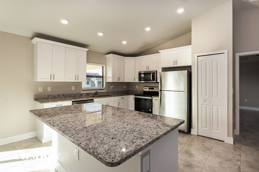 a kitchen with granite counter tops and a stainless steel refrigerator