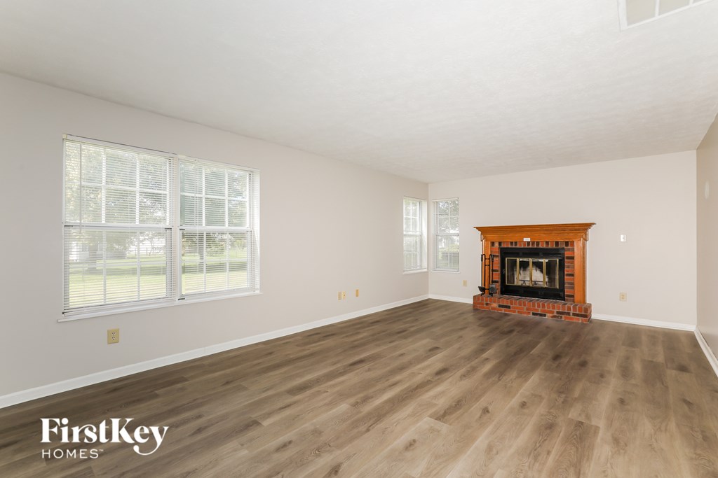 A large empty room with a fireplace and wooden flooring.