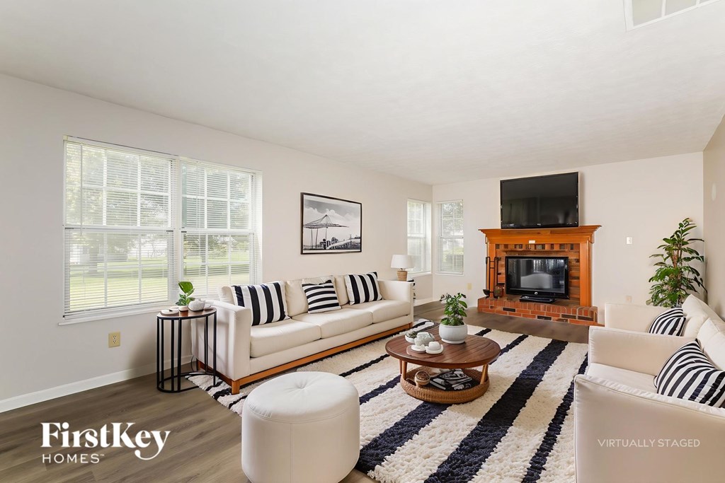 A living room with a white couch, a coffee table, and a fireplace.
