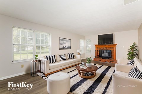 A living room with a white couch, a coffee table, and a fireplace.
