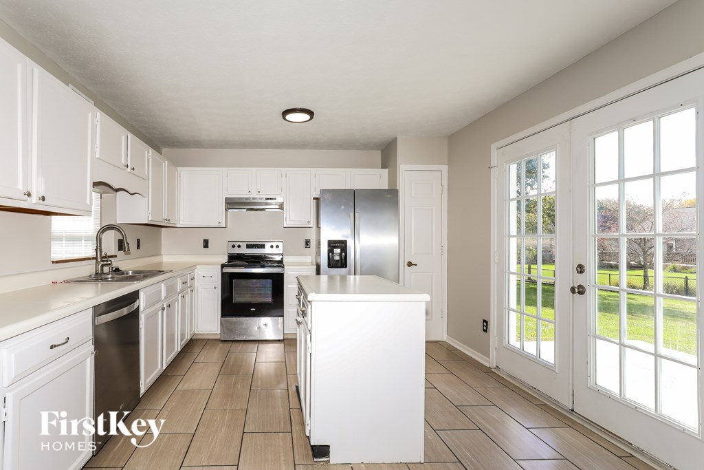 A kitchen with white cabinets and a refrigerator.