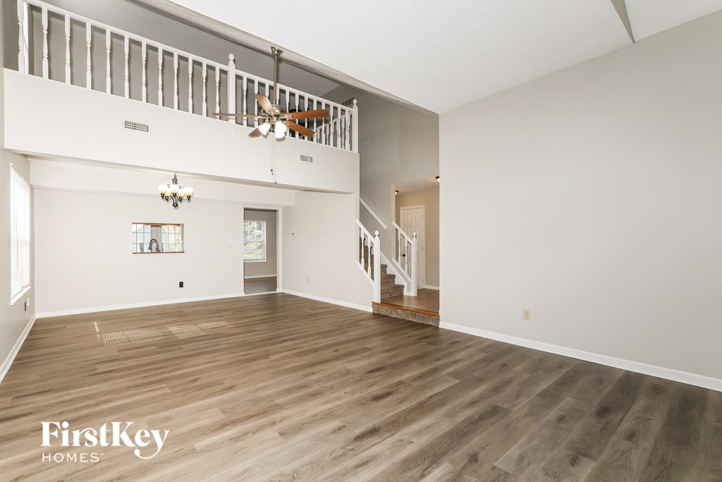 A spacious room with wooden flooring and a staircase leading to another level.