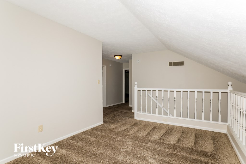 A room with a carpeted floor and a white railing.