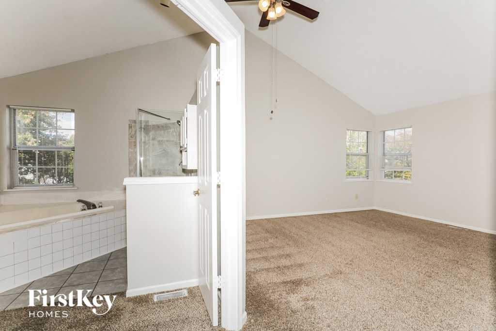 A room with a carpeted floor and a ceiling fan.