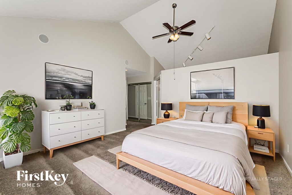 A bedroom with a large bed, a dresser, and a ceiling fan.