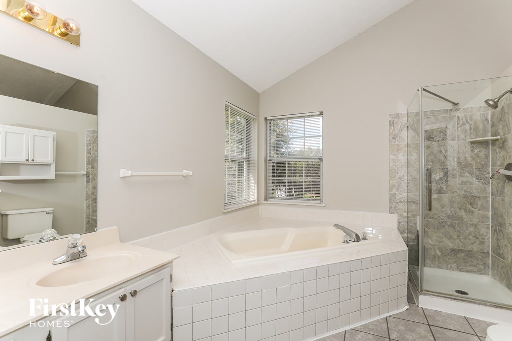 A bathroom with a tub, sink, and shower.
