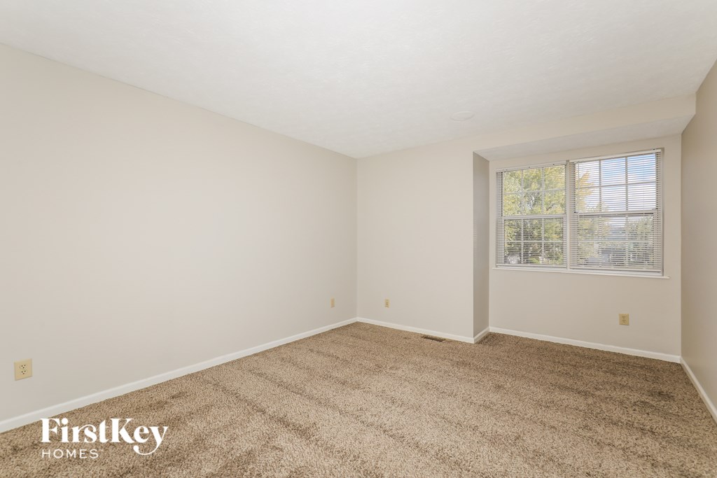 A room with a carpeted floor and a window with blinds.