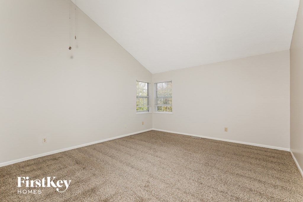 A carpeted room with a window and a FirstKey Homes logo.