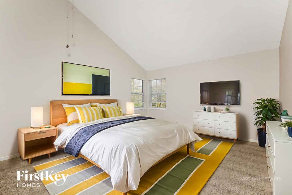 A bedroom with a bed, nightstand, and a painting on the wall.