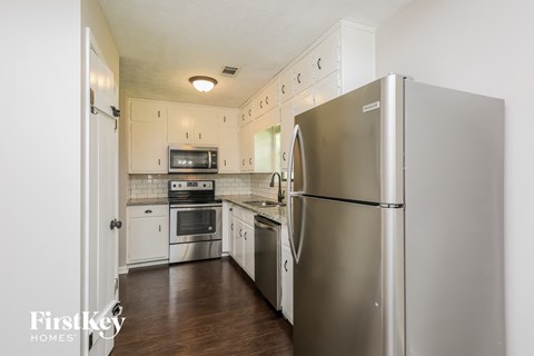 A kitchen with a stainless steel refrigerator and wooden floors.