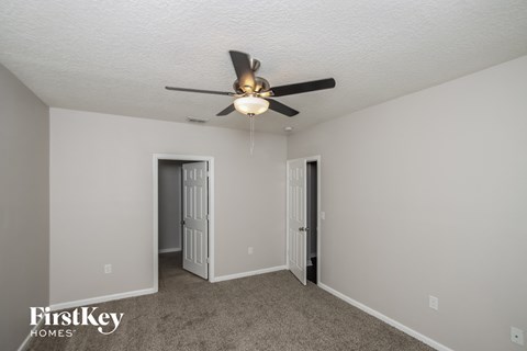a living room with a ceiling fan and a door to a hallway