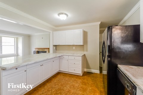 A kitchen with white cabinets and a black fridge.