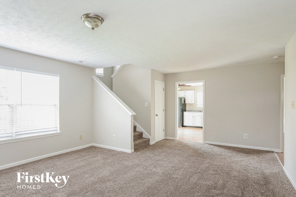 a living room with a carpeted floor and a staircase