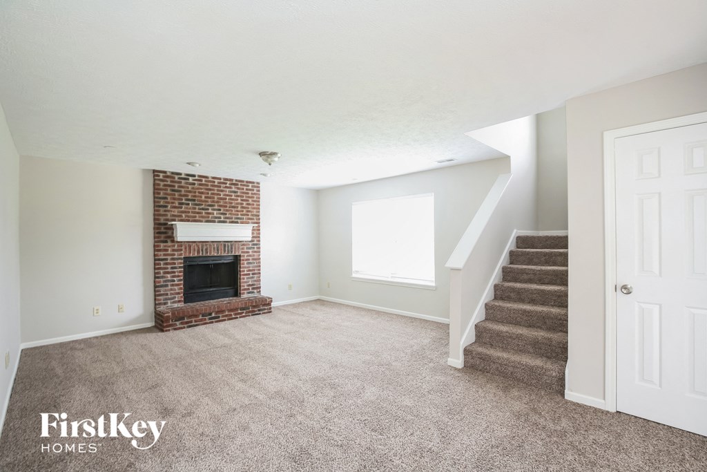 a living room with a fireplace and carpeted stairs