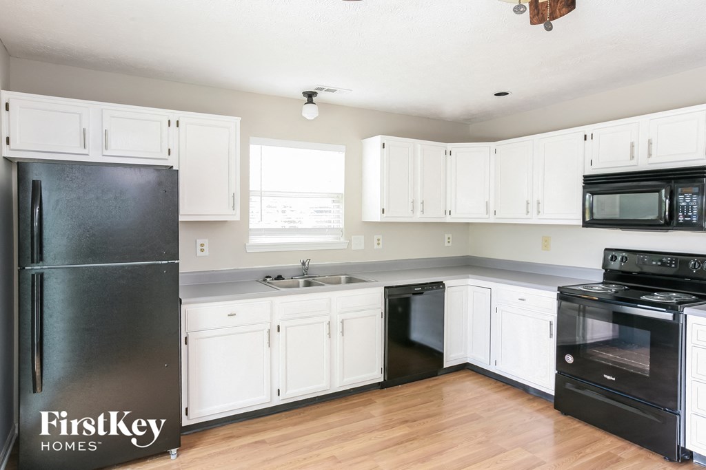 a kitchen with white cabinets and black appliances