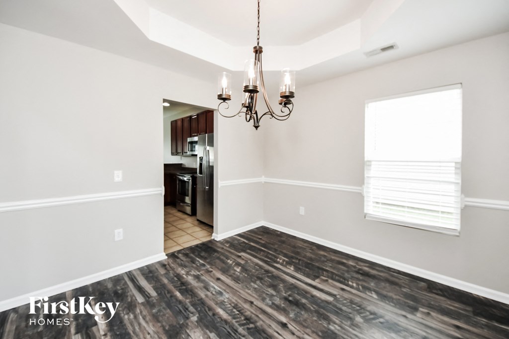 an empty living room with a chandelier and a kitchen