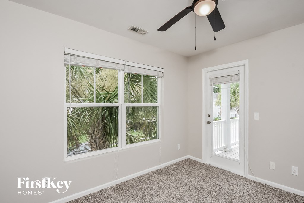 a bedroom with a large window and a ceiling fan