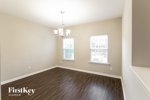 a dining room with wood flooring and two windows