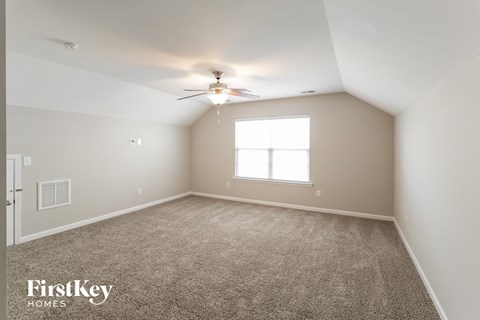 a bedroom with carpet and a ceiling fan and a window
