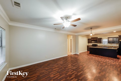 A spacious room with a ceiling fan and wooden flooring.