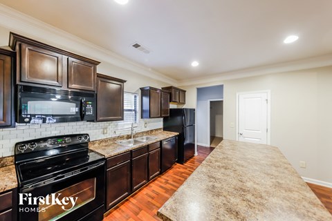 A kitchen with a black stove top oven and a black refrigerator.