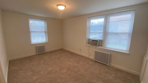 A room with two windows and radiators under the windows.