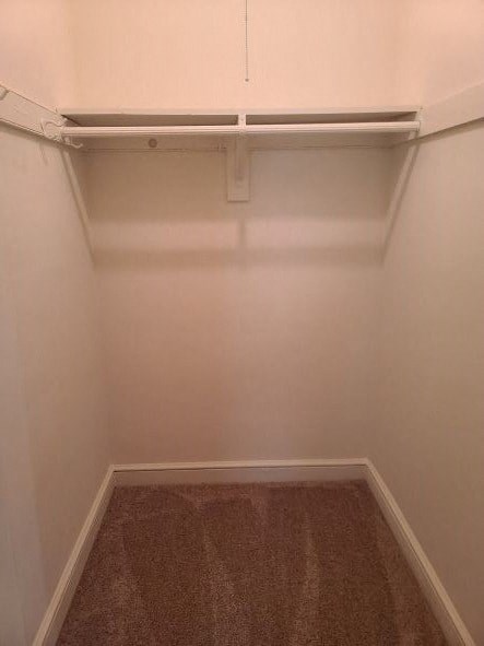 A small, empty room with a carpeted floor and a white wall.