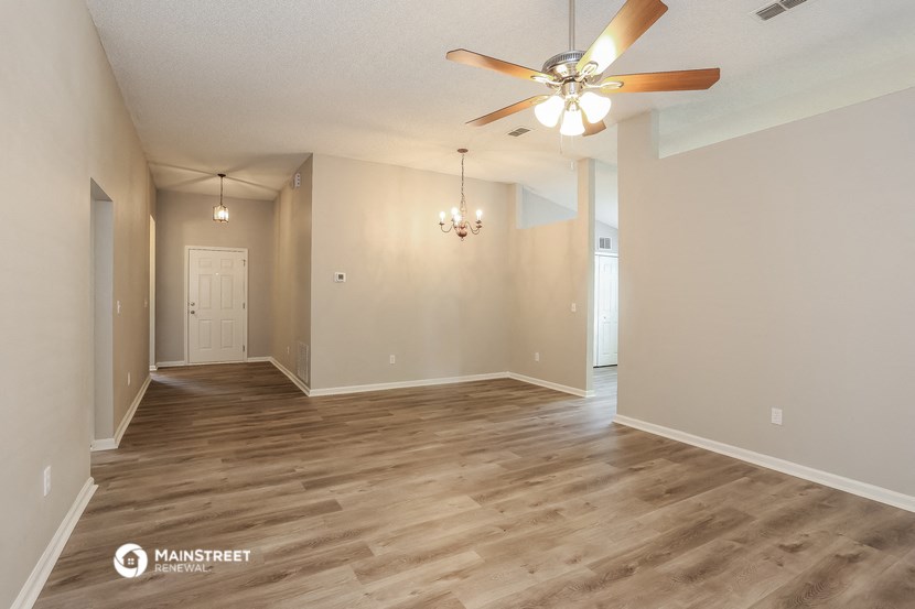 the spacious living room and dining room with wood flooring and a ceiling fan