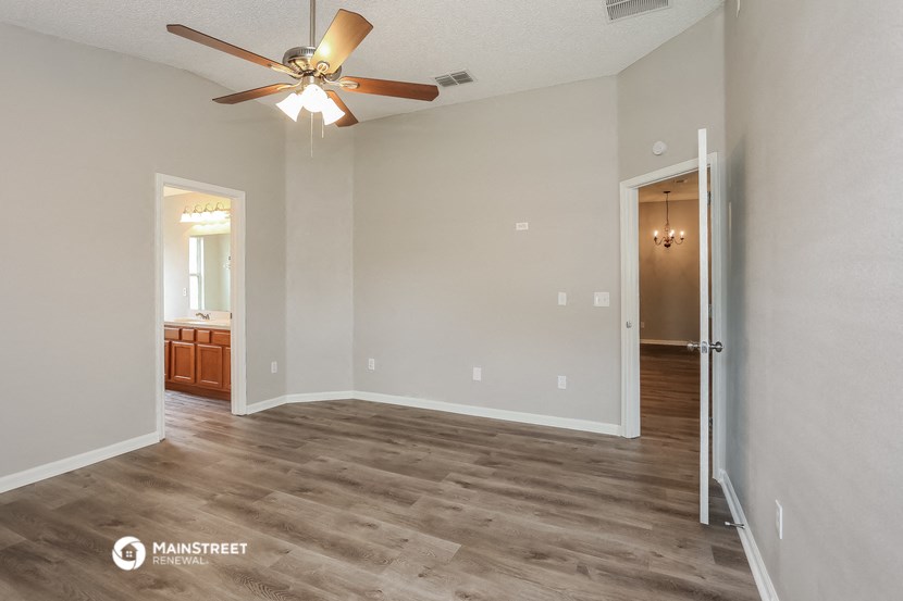 a living room with a ceiling fan and a door to a bathroom