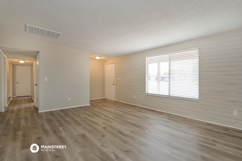 the living room of an apartment with wood flooring and a window