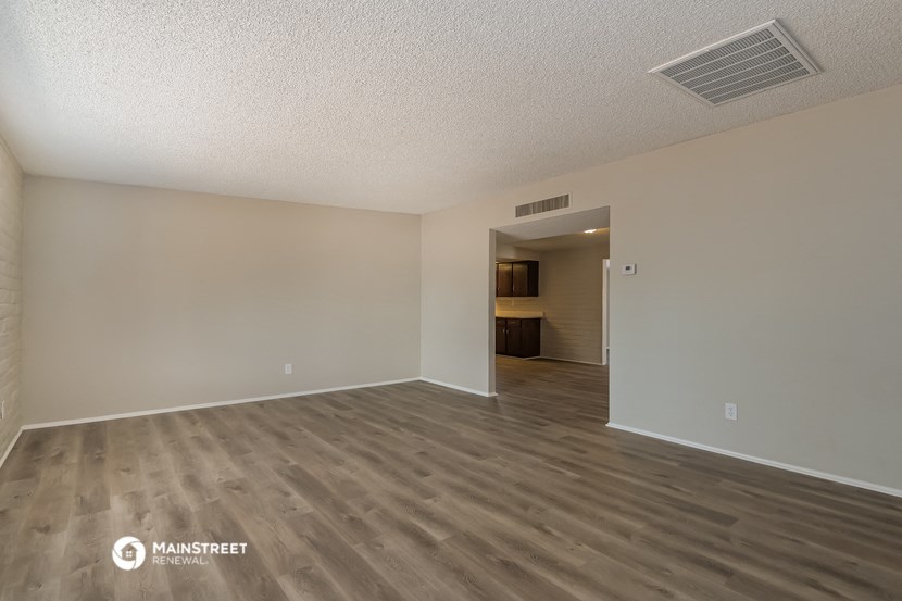 the spacious living room with wood flooring and white walls