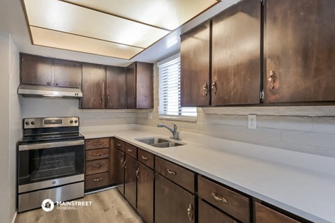 a kitchen with a sink and stove and wooden cabinets
