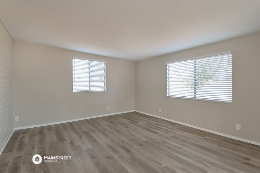 the spacious living room with wood flooring and two windows