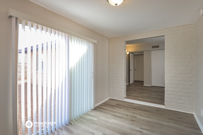 a view of a living room and a hallway with white blinds on a window