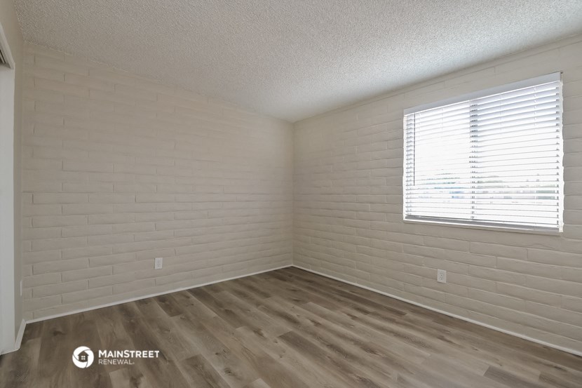 the interior of an empty room with wood flooring and a window