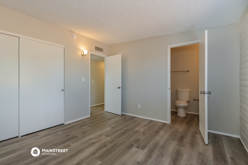 the living room of an apartment with a toilet and two closets