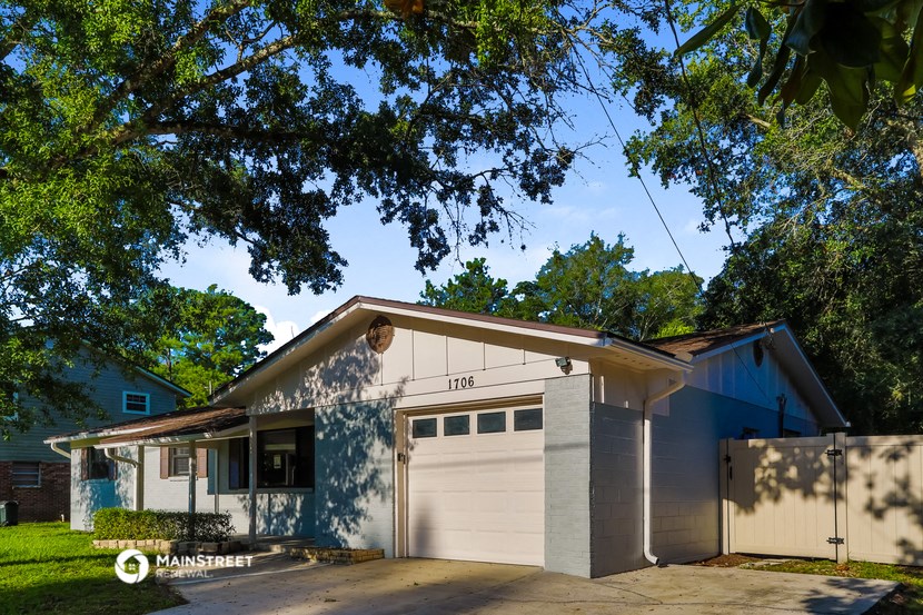 a white house with a garage and a tree