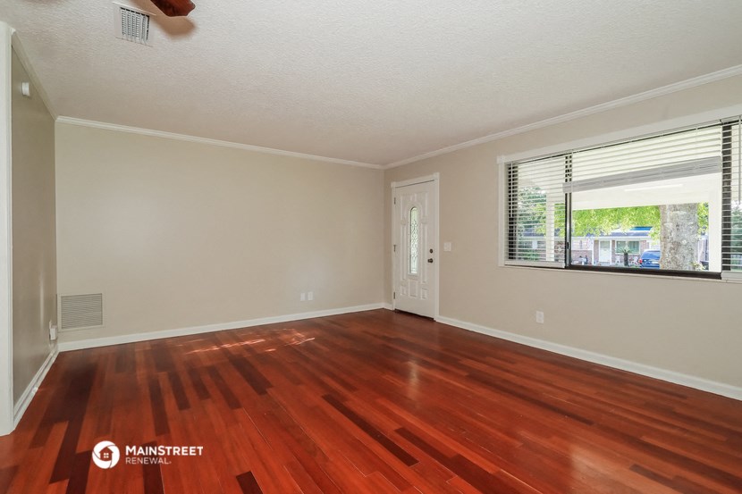 an empty living room with wood floors and a window
