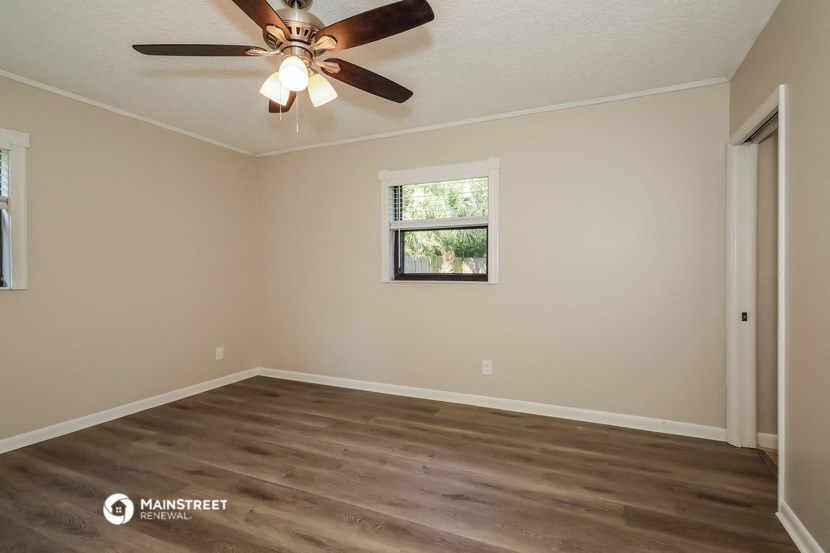 the spacious living room with wood floors and a ceiling fan