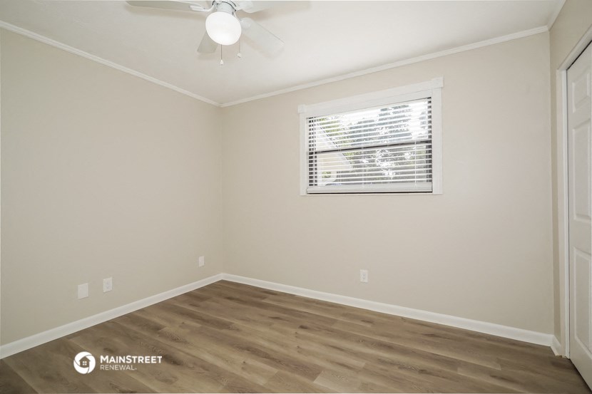 a bedroom with a window and a ceiling fan