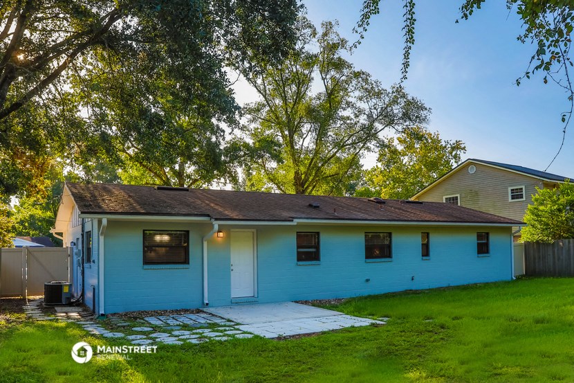 the back of a blue house with a yard and trees