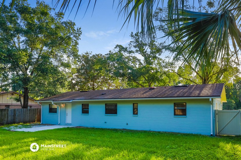 a blue house with a yard and a palm tree