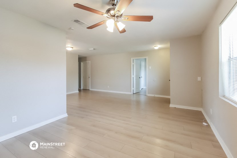 an empty living room with a ceiling fan