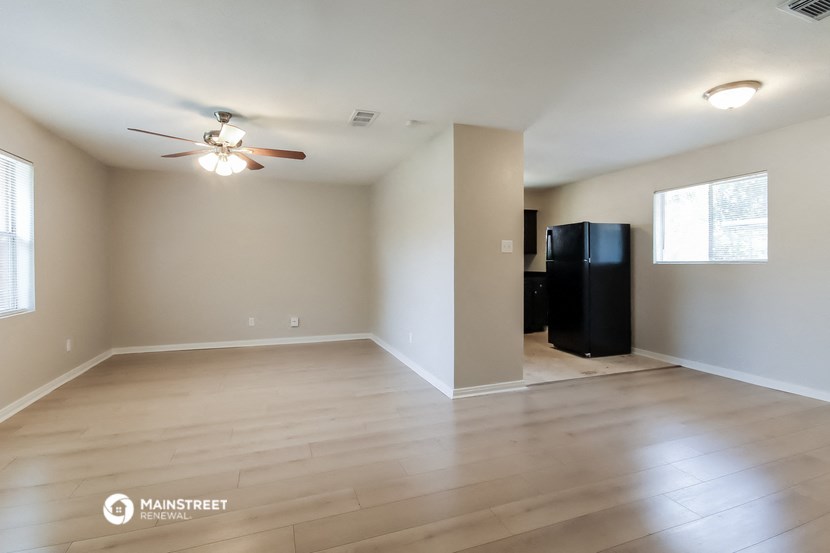 the spacious living room with hardwood floors and a ceiling fan