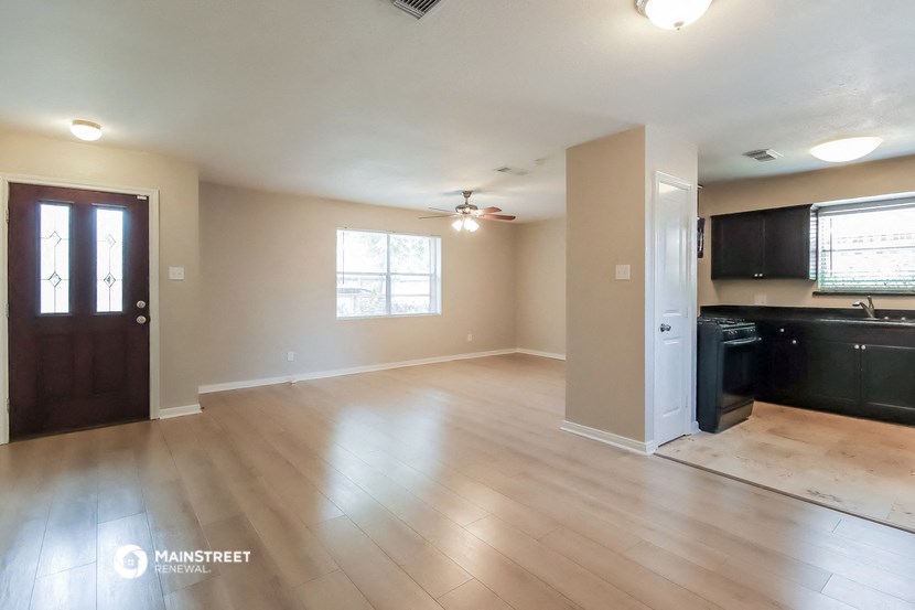 an empty living room and kitchen with wood flooring