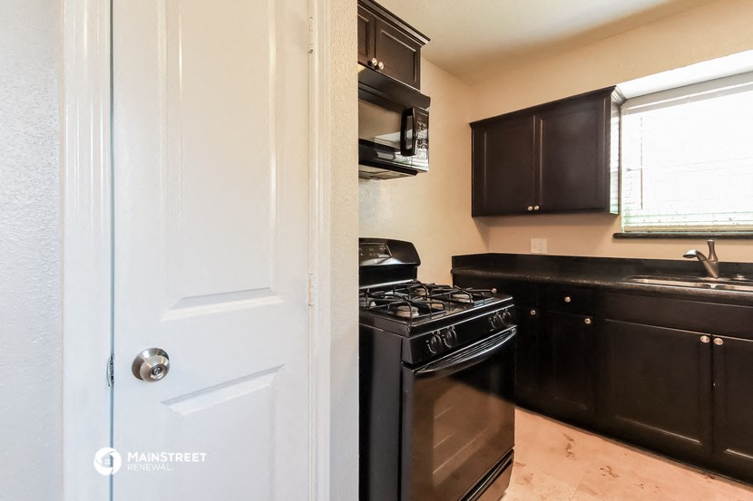 a kitchen with black appliances and black cabinets and a white door