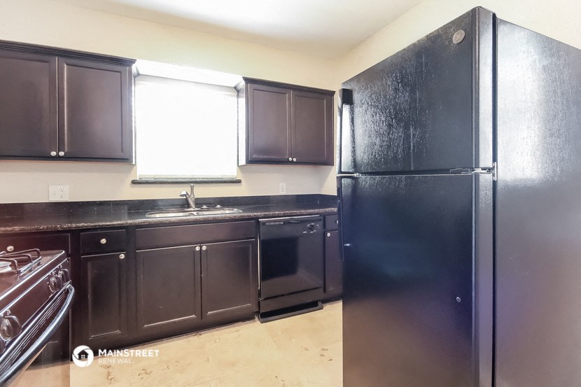 a kitchen with black cabinets and a black refrigerator