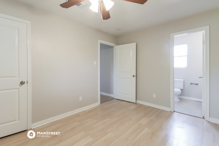 an empty living room with a door to the bathroom and a toilet