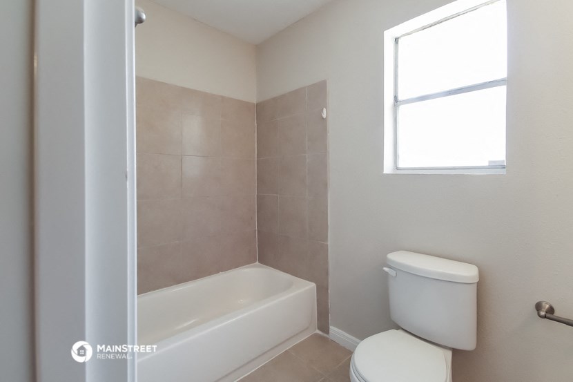a bathroom with a toilet and a tub and a window
